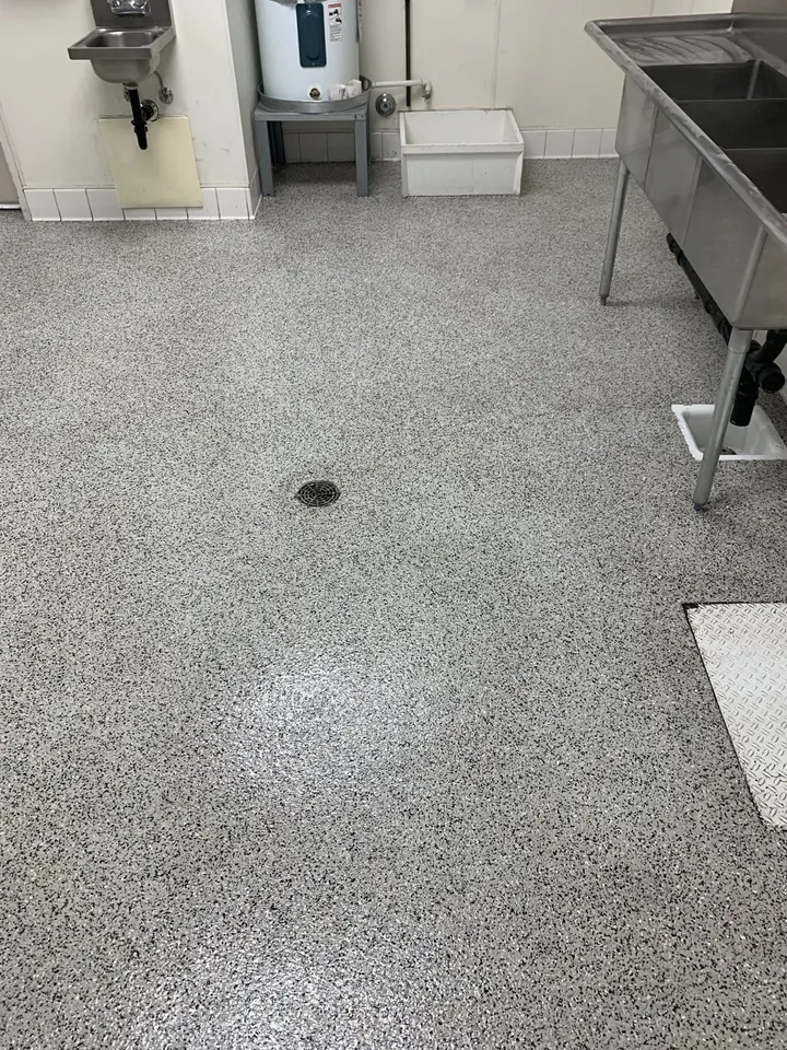 Gray broadcast floor around a floor drain in a commercial kitchen