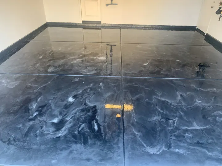Gray and blue metallic epoxy garage floor with a dark cove border